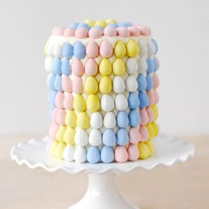 Cadbury mini eggs layer cake on a white cake stand.