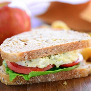 An egg salad sandwich on wheat bread with lettuce and tomatoes.