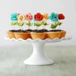Flower pot cookie cups on a white cake stand.