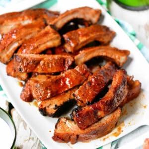 Grilled barbecue ribs on a white serving platter.