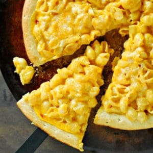 Macaroni and cheese pizza with a slice removed.