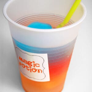 A colorful fruit-flavored magic potion rainbow drink in a plastic cup.