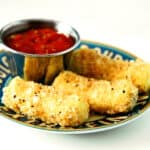 Mozzarella cheese sticks on a plate with dipping sauce.
