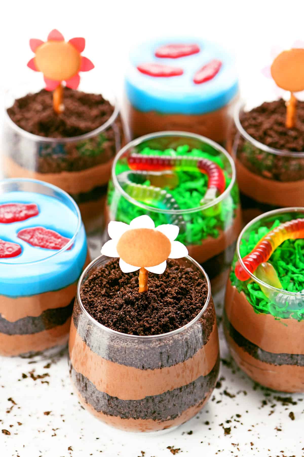 Dirt cake cups with chocolate pudding and crushed Oreos with gummy fish, edible flowers, and gummy worms.