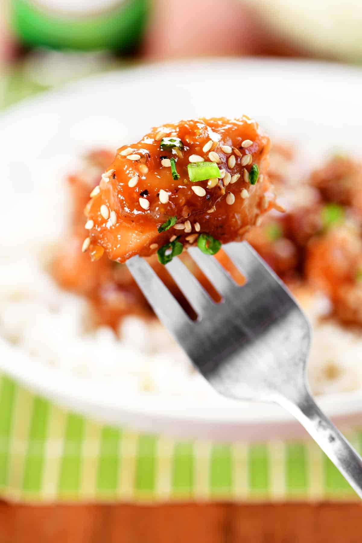 A piece of honey sesame chicken on a fork.