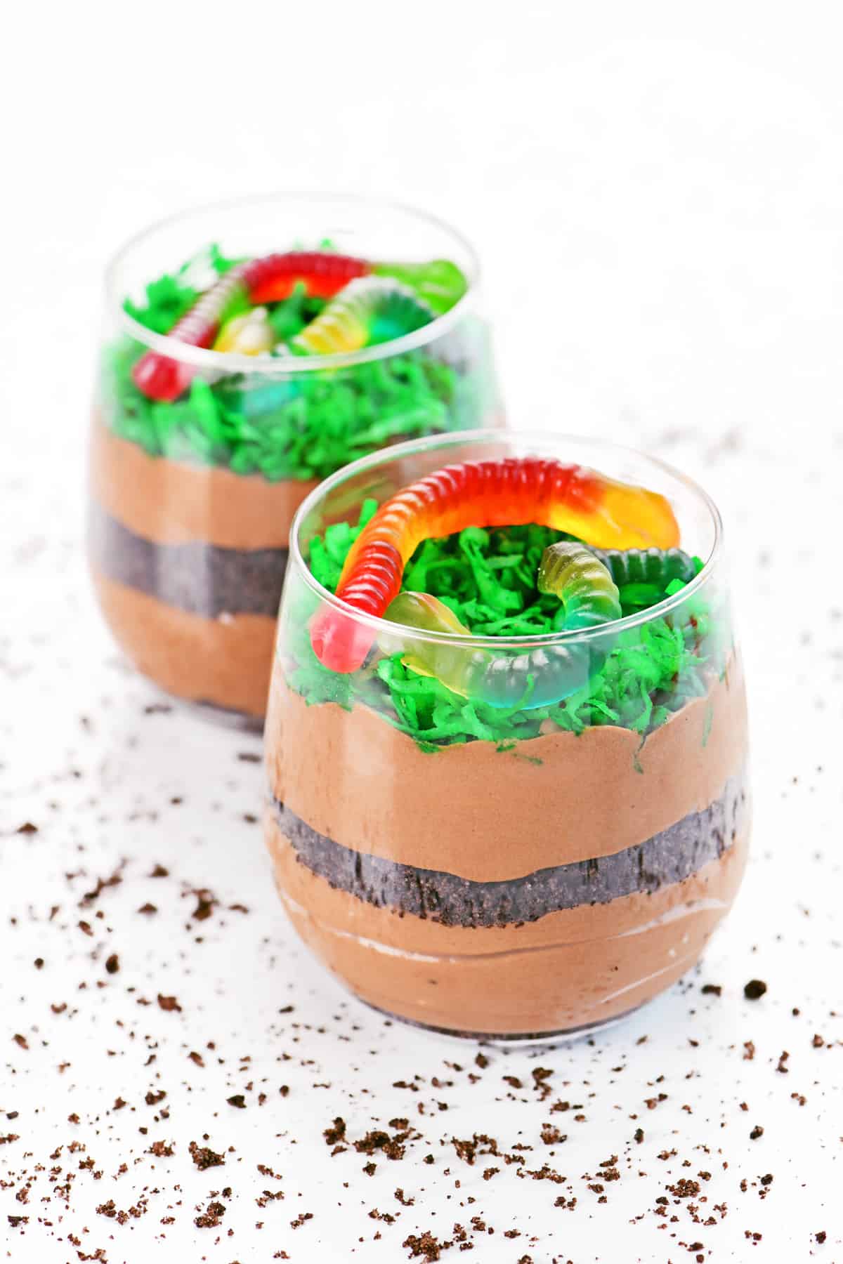 Dirt cake cups with crushed Oreos and chocolate pudding topped with green coconut and gummy worms.
