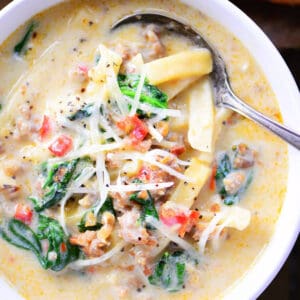 A white bowl that is full of Italian sausage soup.