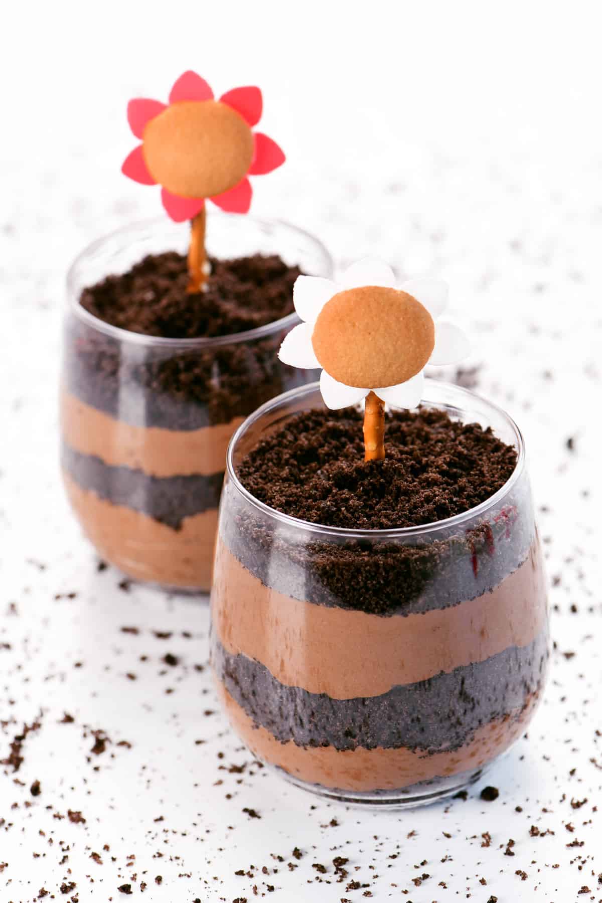 Dirt cake cups with crushed Oreos and chocolate pudding with edible flowers on top.