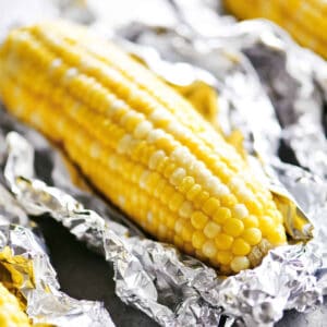 An ear of oven roasted corn on the cob sitting on foil.