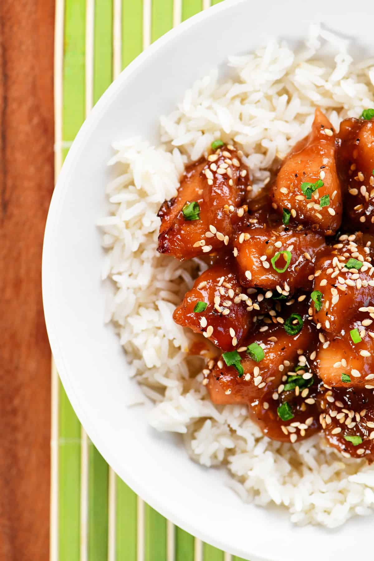 Slow cooker sesame chicken in a white bowl over rice.