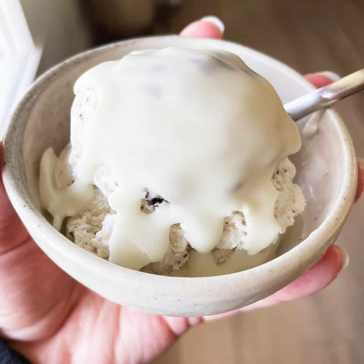 Magic white chocolate shell sauce on cookies and cream ice cream in a stoneware bowl.