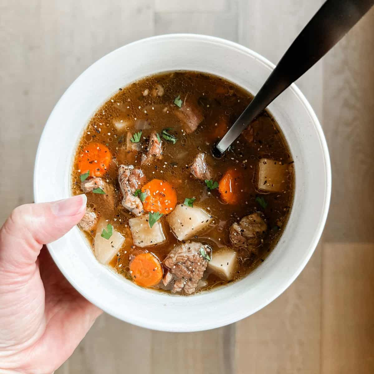 Tonia Larson holding a bowl of slow cooker beef stew.