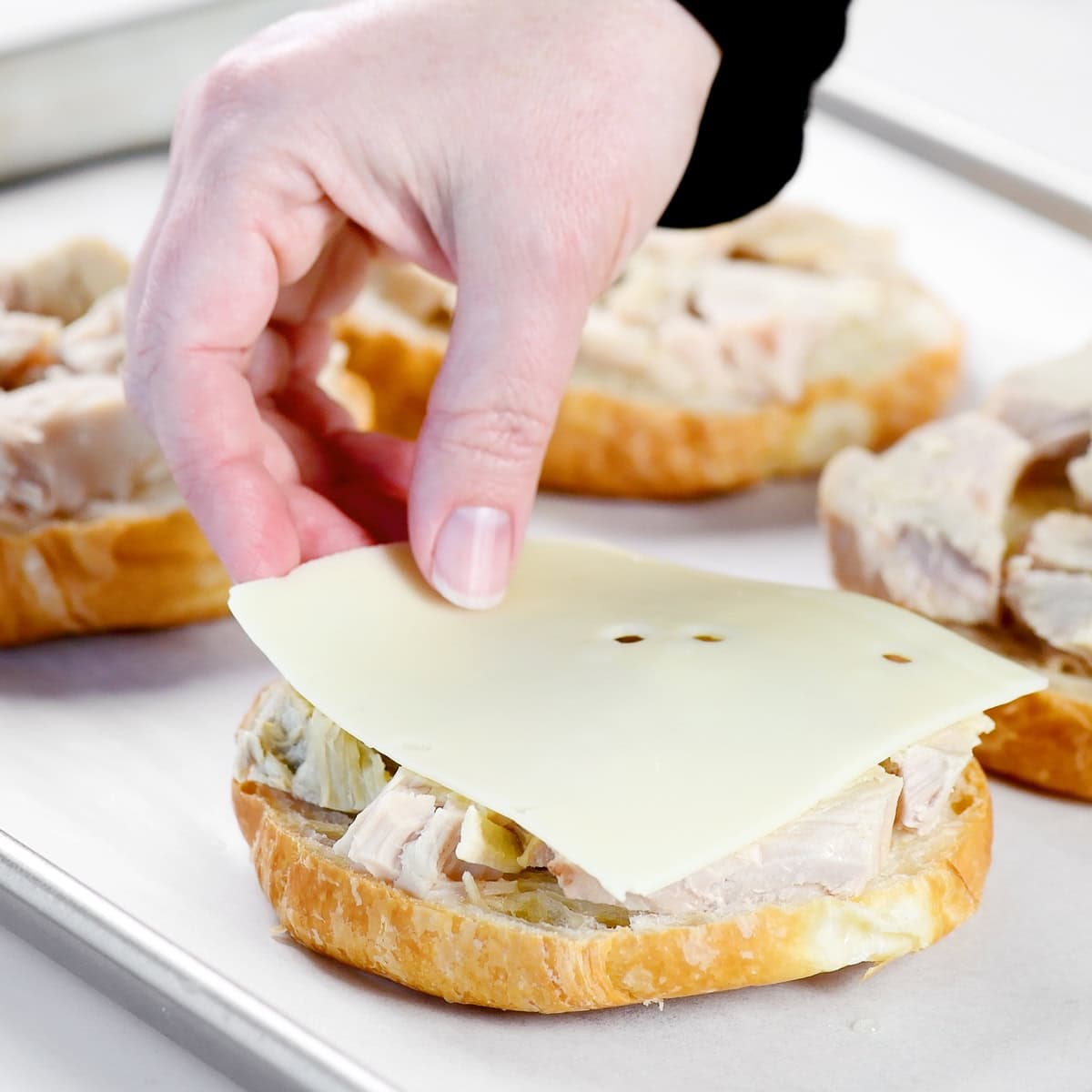 Adding a slice of Swiss cheese.