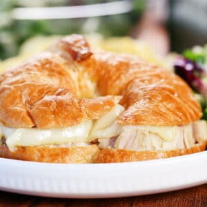 Turkey croissant with cheese on a white plate.