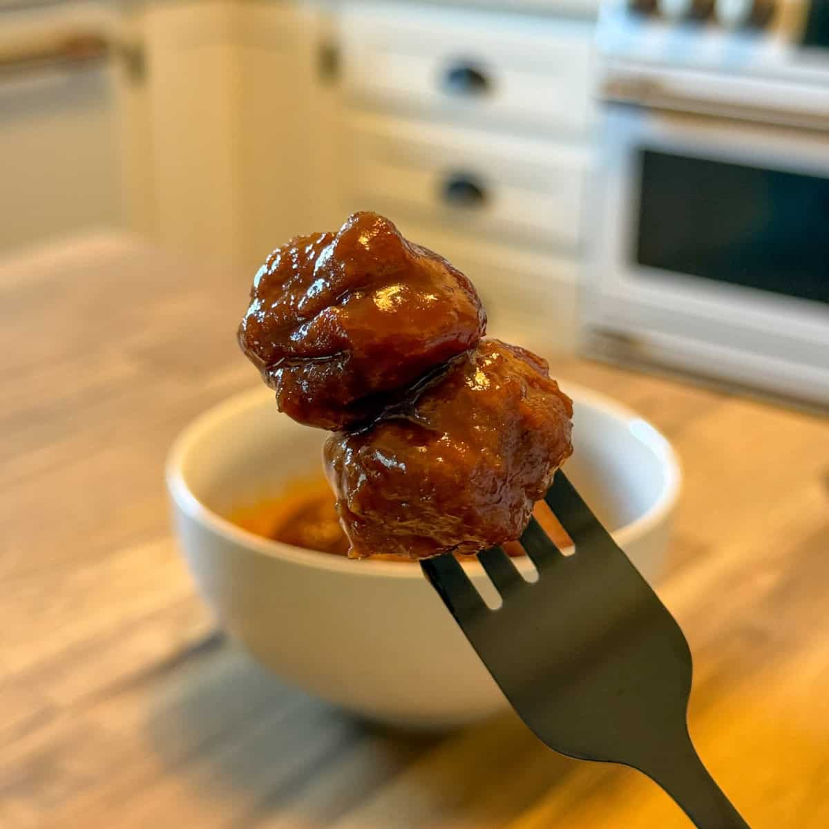 Two grape jelly meatballs on a fork.