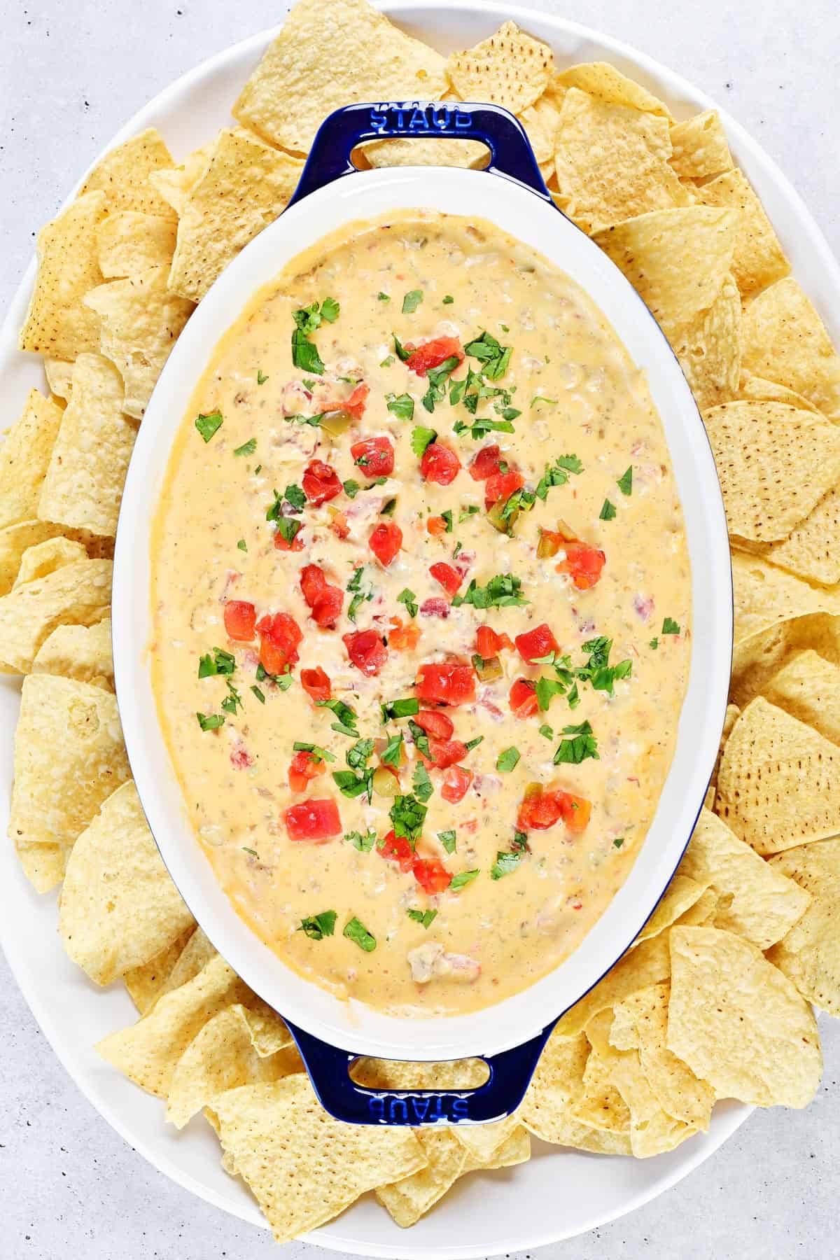 A platter with sausage queso dip and tortilla chips.