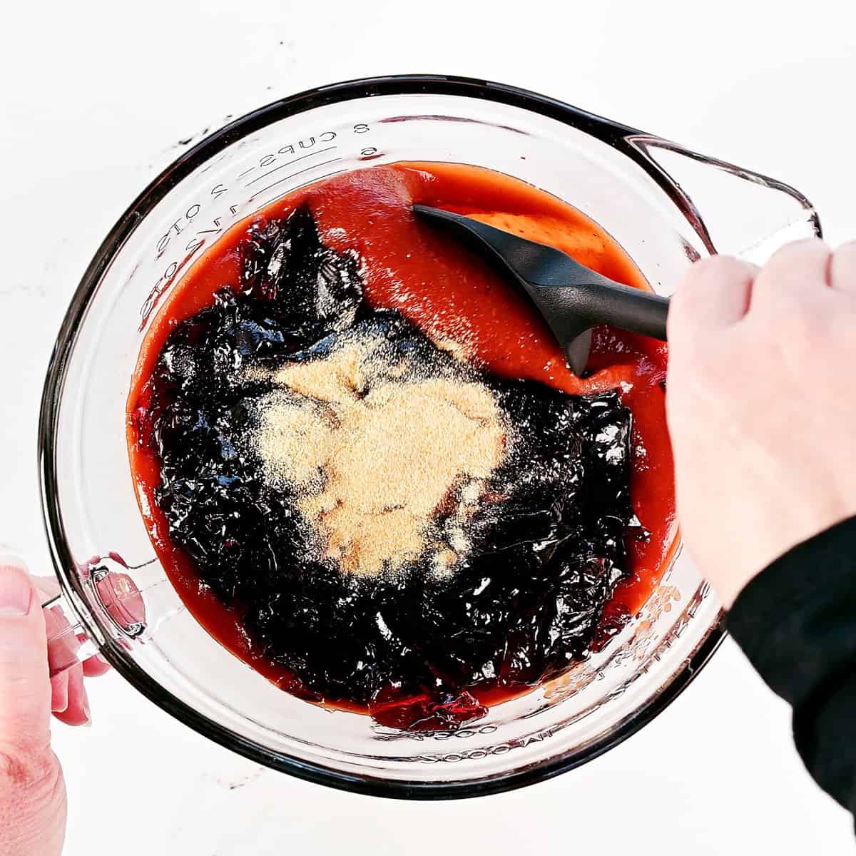 Stirring ingredients in a glass bowl with a silicone spatula.