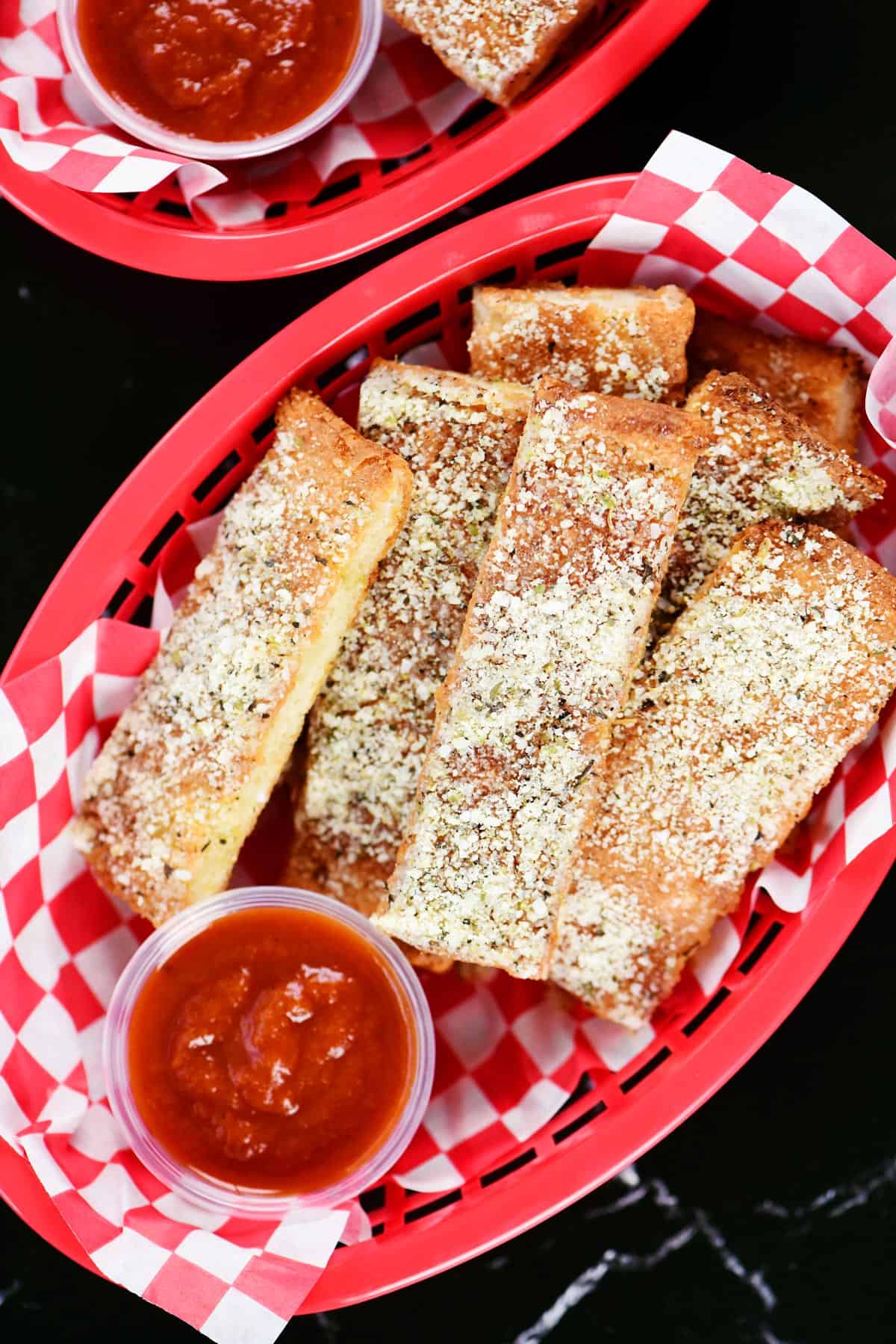 Cottage cheese breadsticks in red plastic oval baskets lined with red checked deli paper.