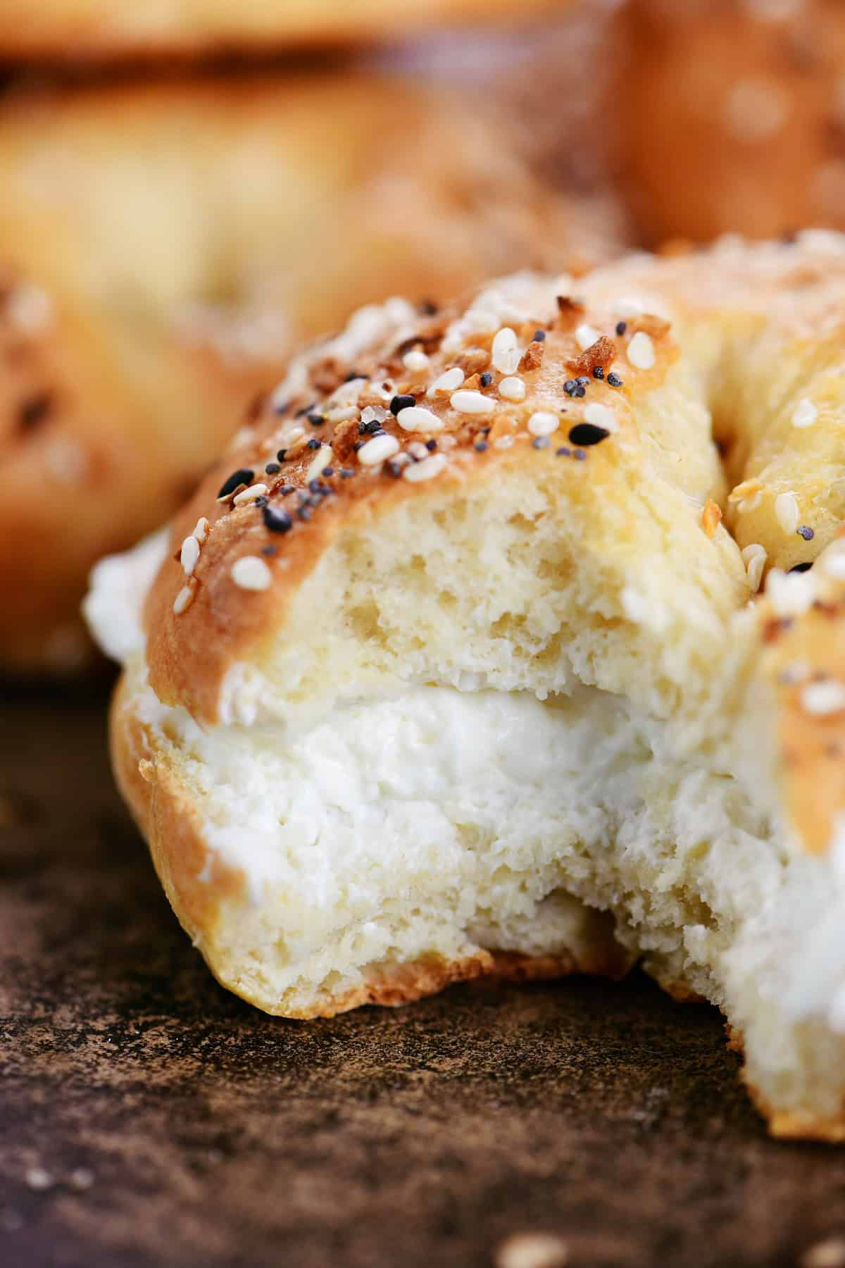 A bite removed from a cottage cheese bagel with cream cheese.