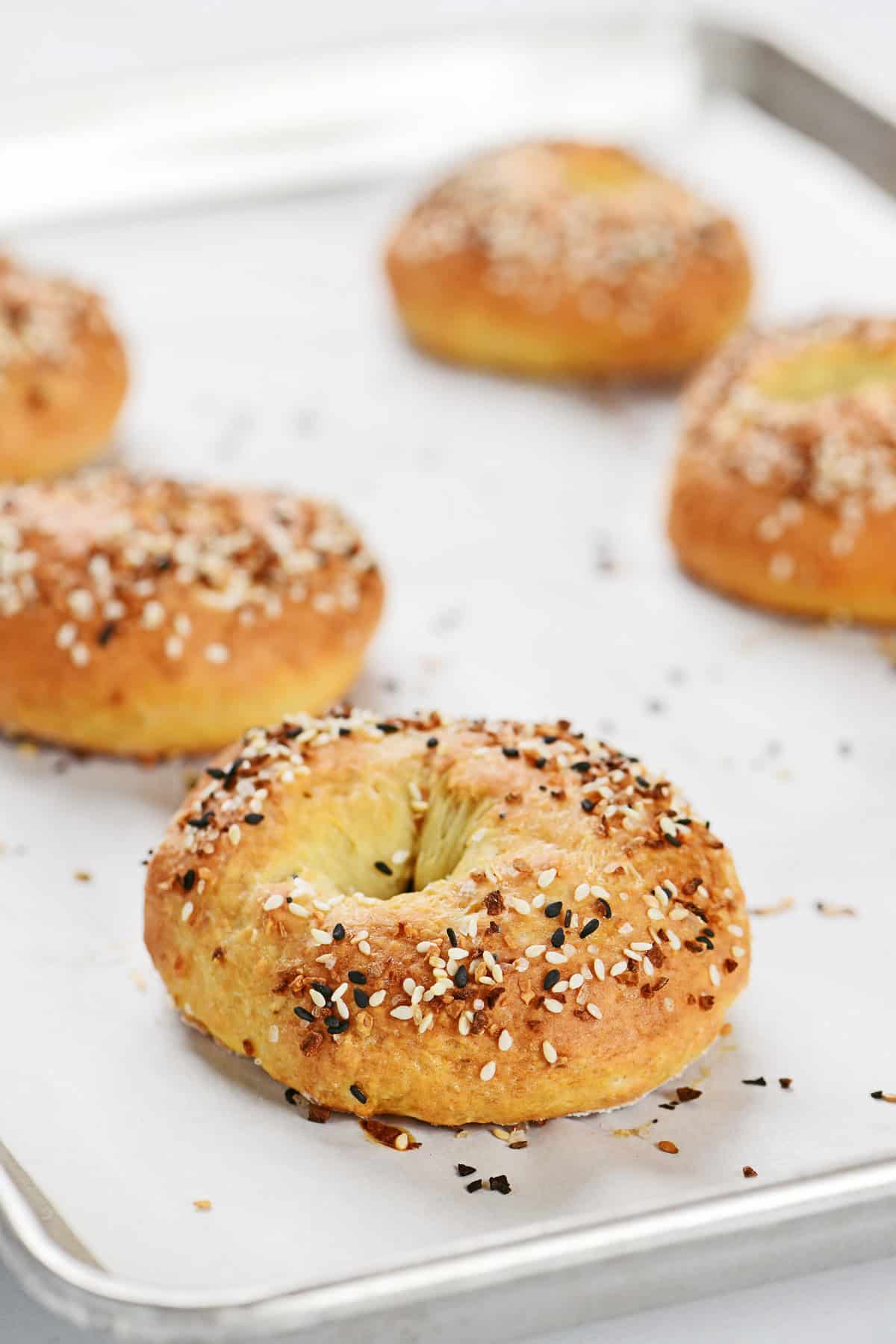 Baked cottage cheese bagels on a parchment-lined baking sheet.