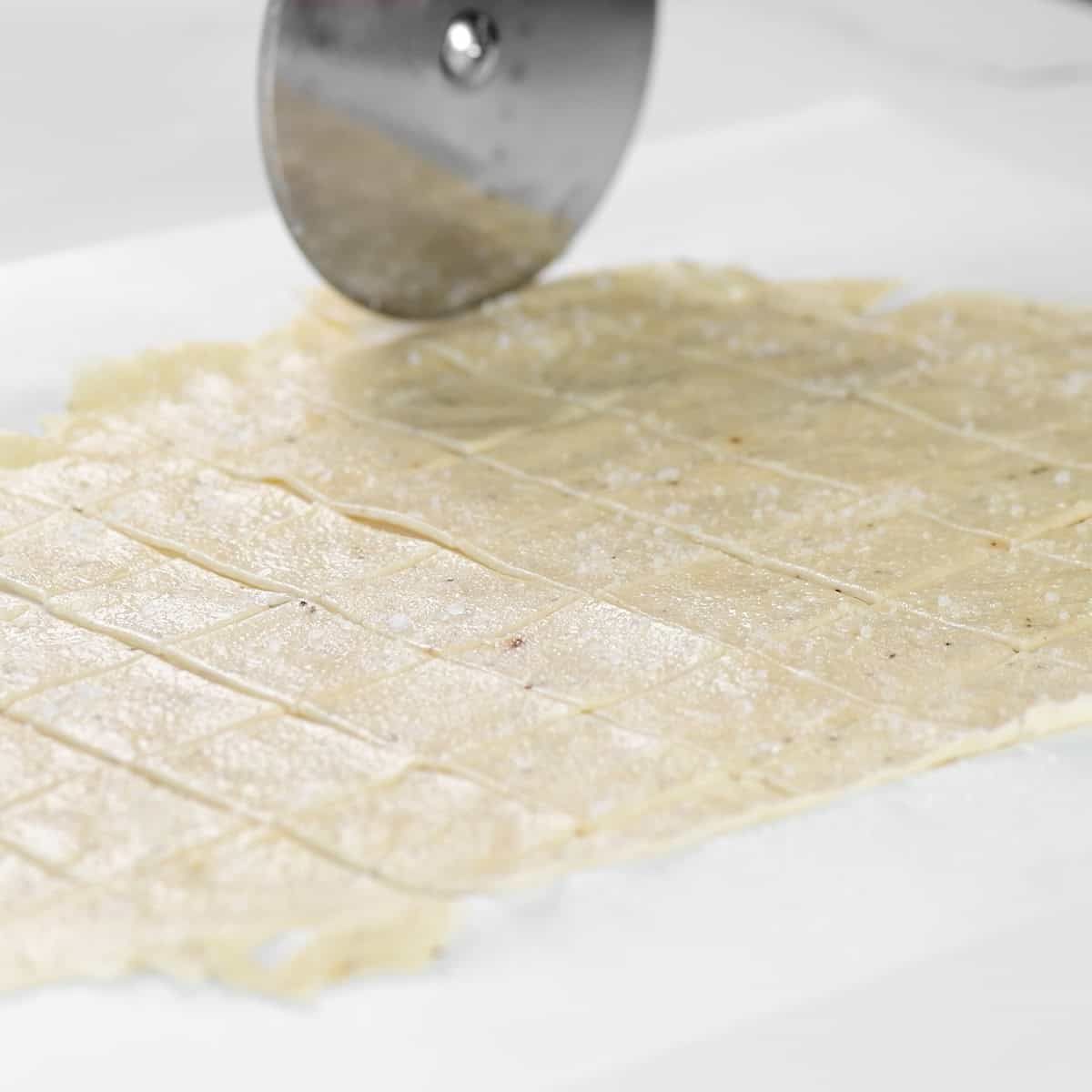 Cutting dough into squares with a pizza cutter.