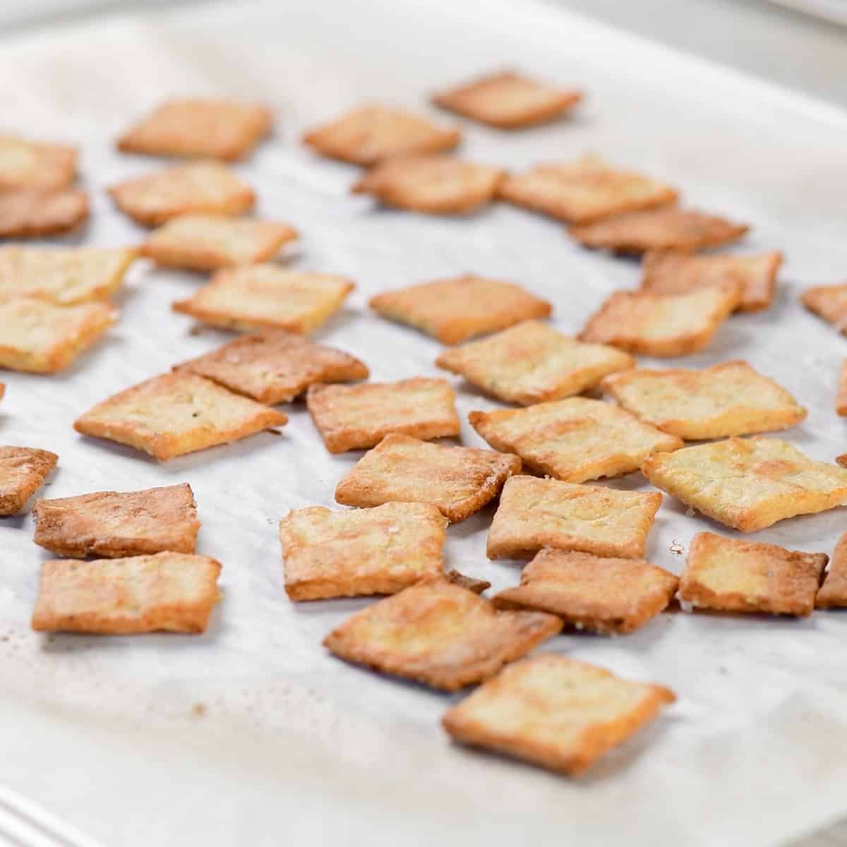 Golden brown cottage cheese crackers on a parchment-lined baking sheet.
