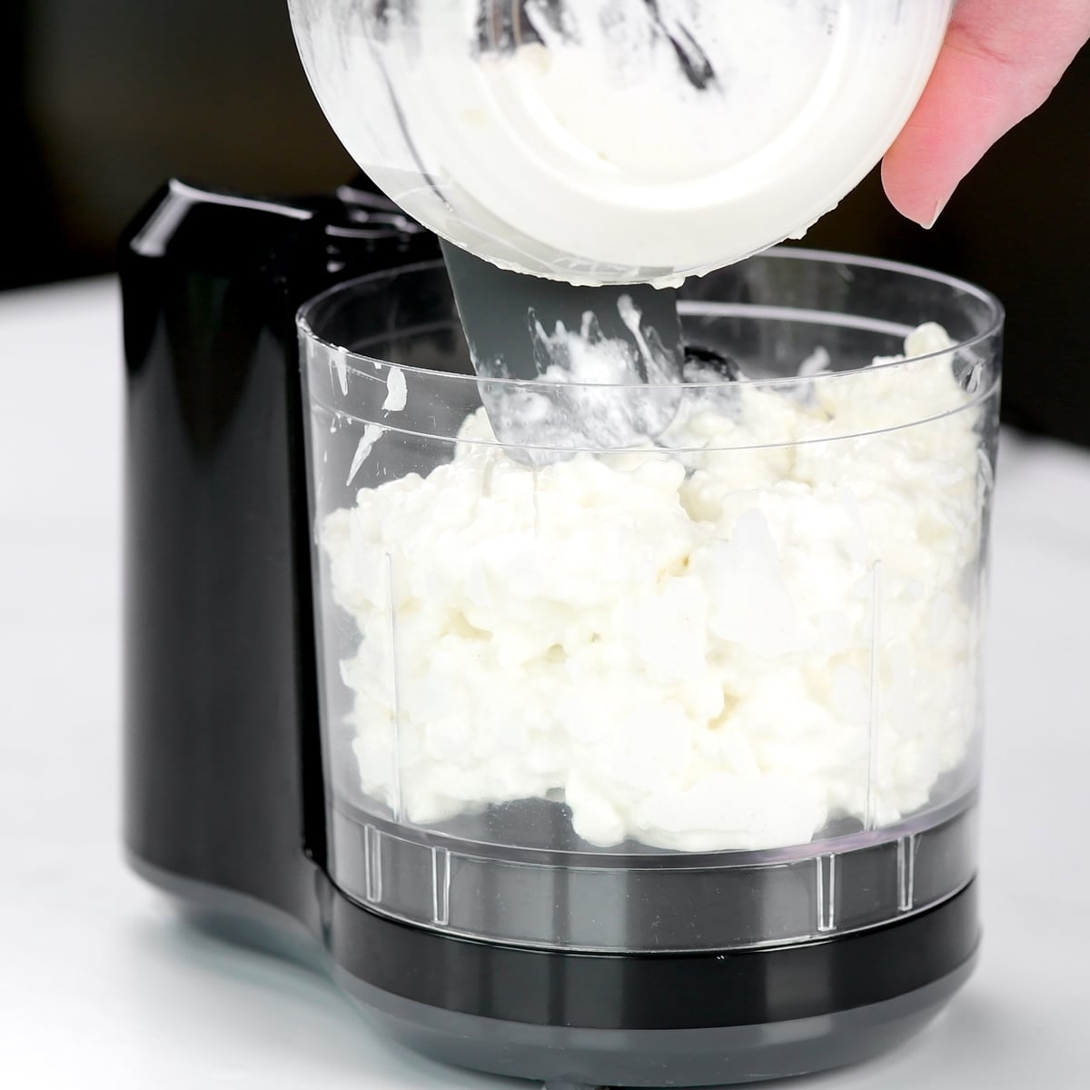 Putting cottage cheese into a mini food processor.