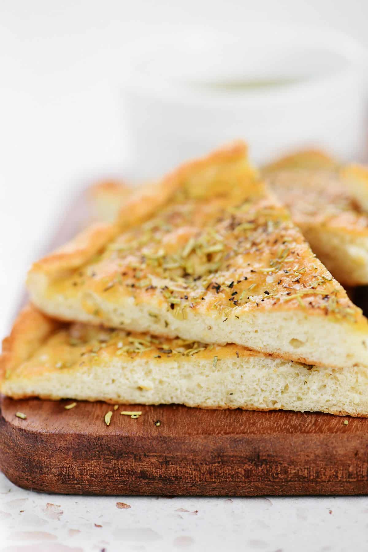 Two slices of cottage cheese focaccia stacked on a wood cutting board.