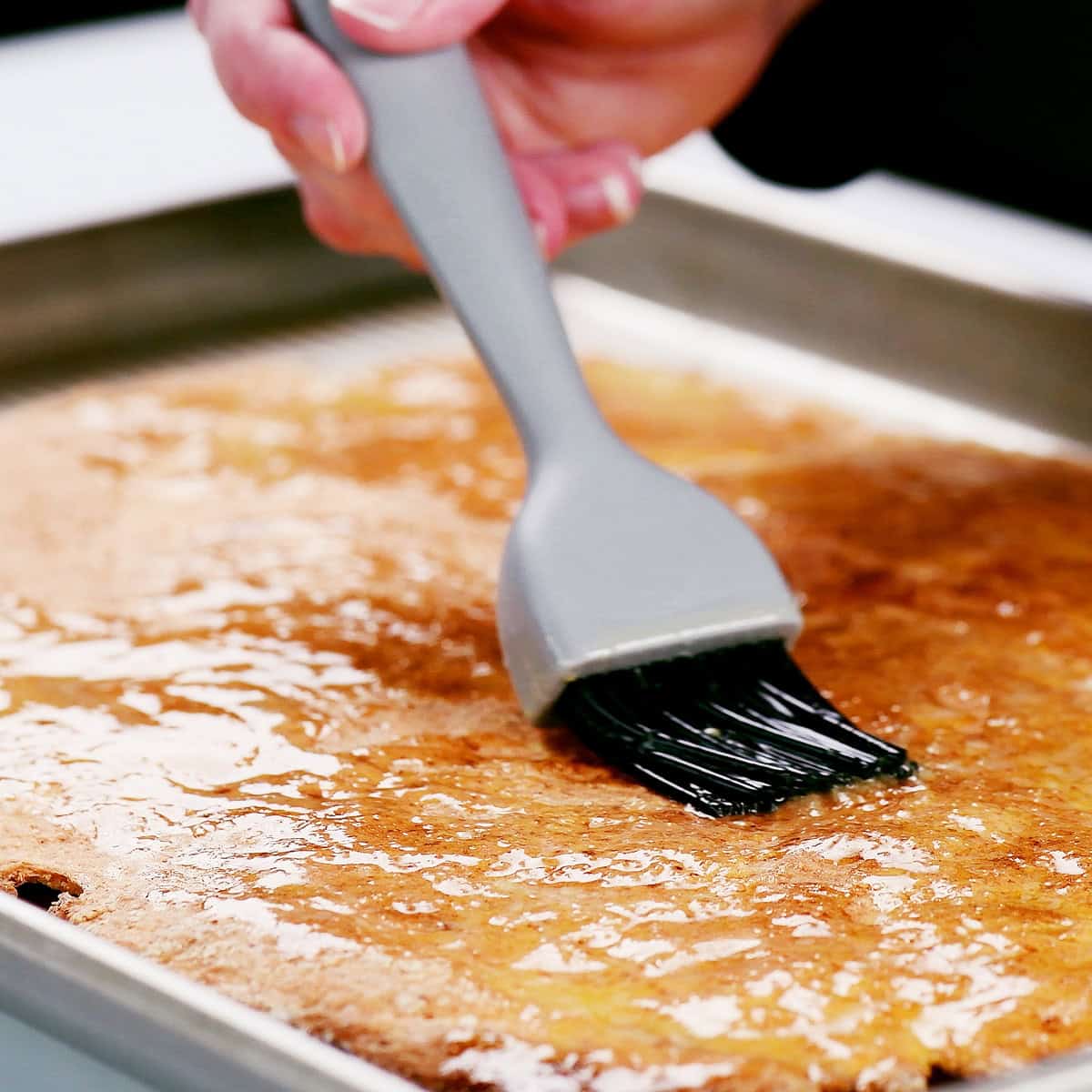 Brushing garlic butter over the cottage cheese pizza crust.