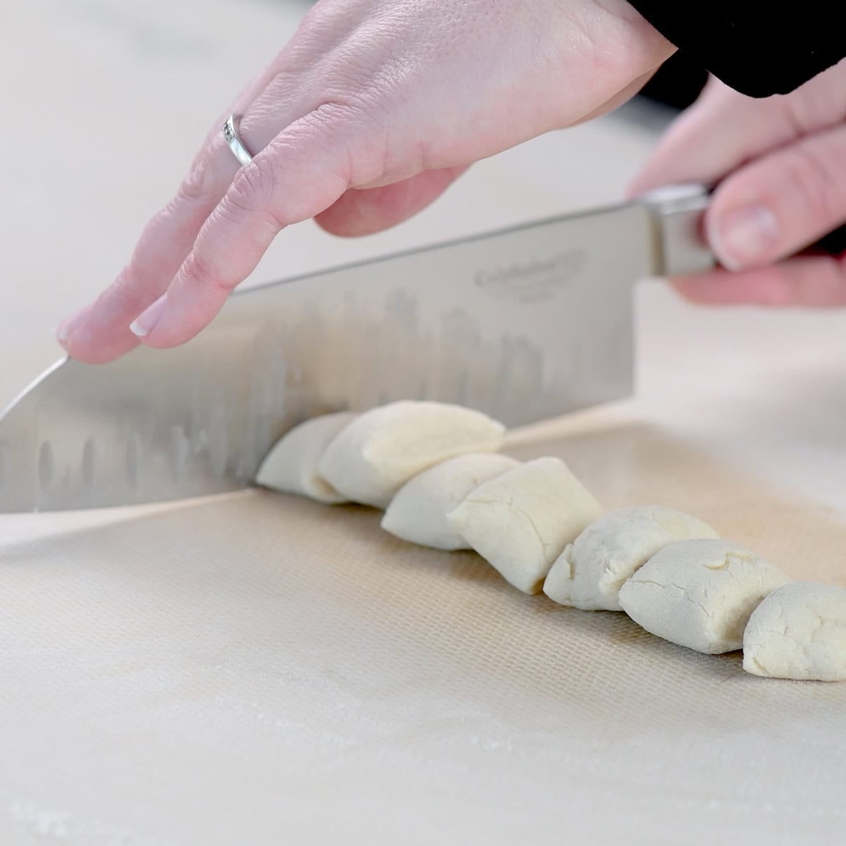 Cutting a length of dough into equal pieces.