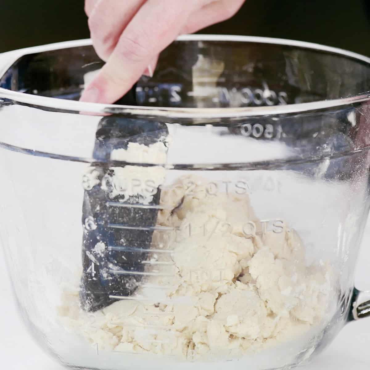 Mixing dough in a glass bowl with a black spoon.