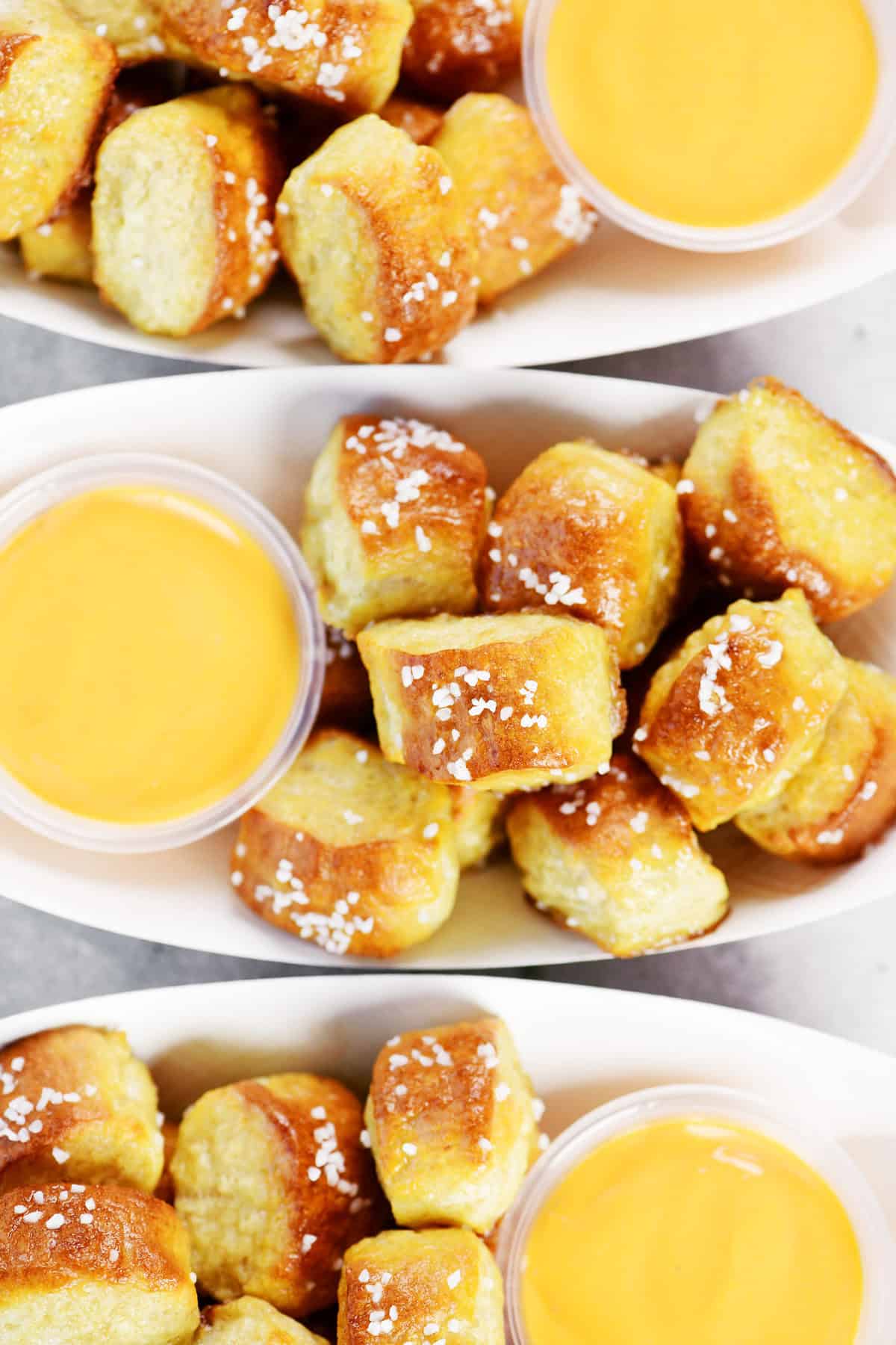Cottage cheese pretzel bites in three paper trays with cheese dip.