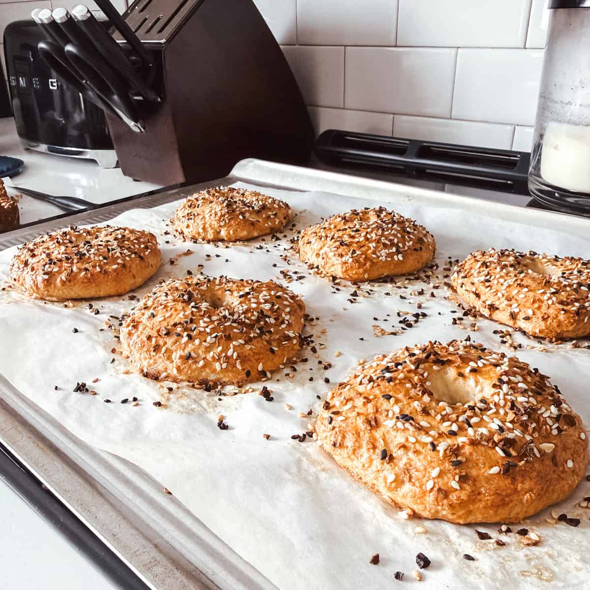 Cottage cheese bagels on a baking sheet on a stovetop in a kitchen.