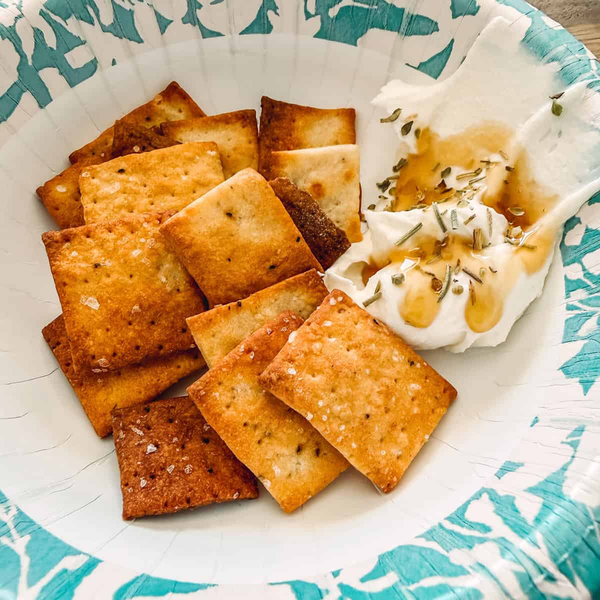 Cottage cheese crackers and a dip in a floral paper bowl.