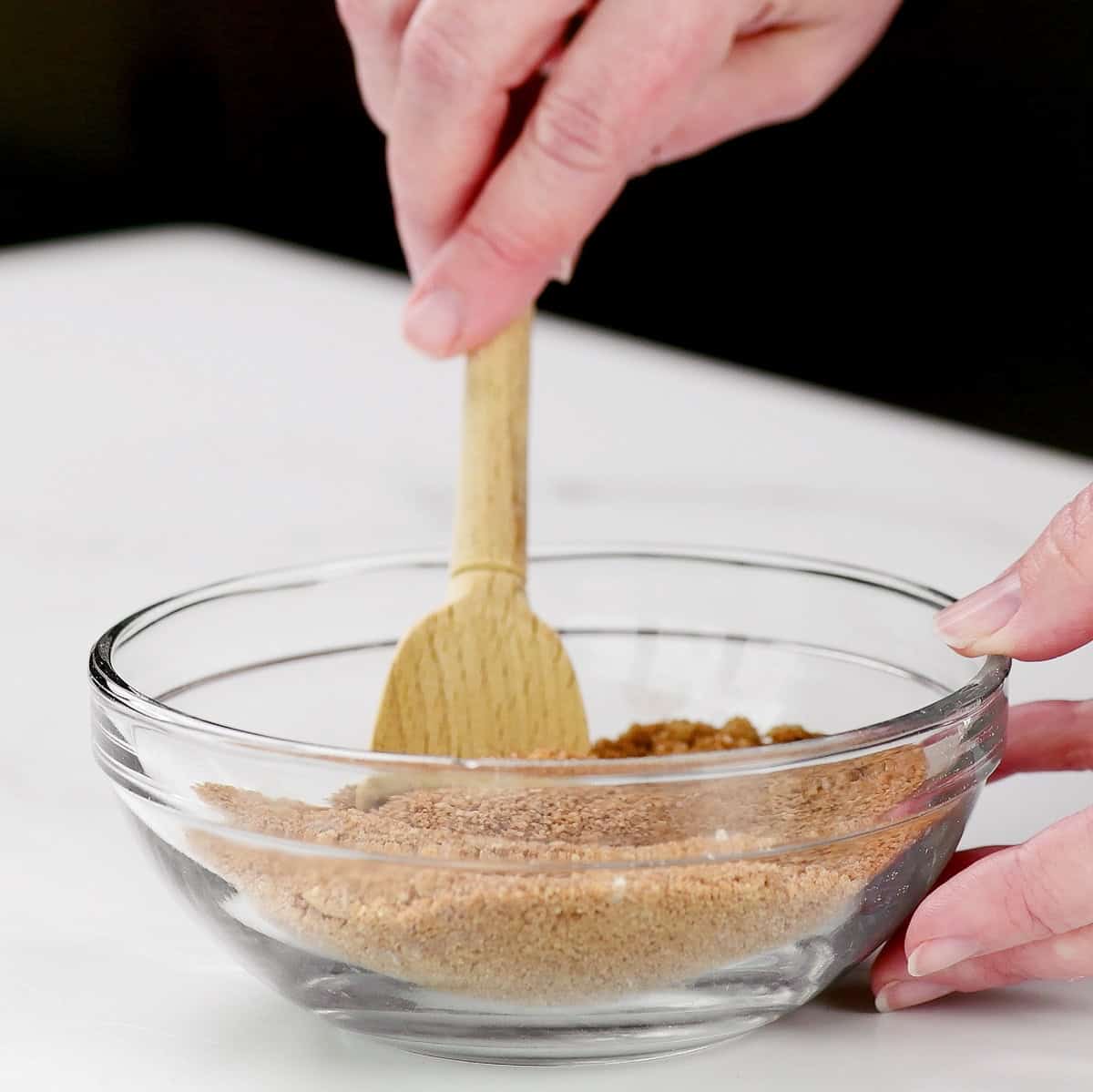 Mixing the cinnamon sugar topping in a small glass bowl with a wooden spoon.