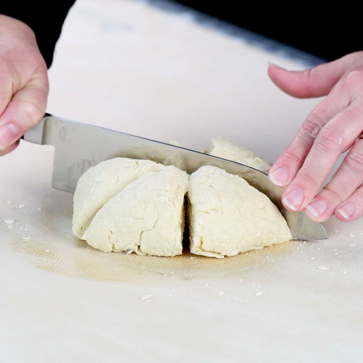 Cutting cottage cheese flatbread dough into wedges.