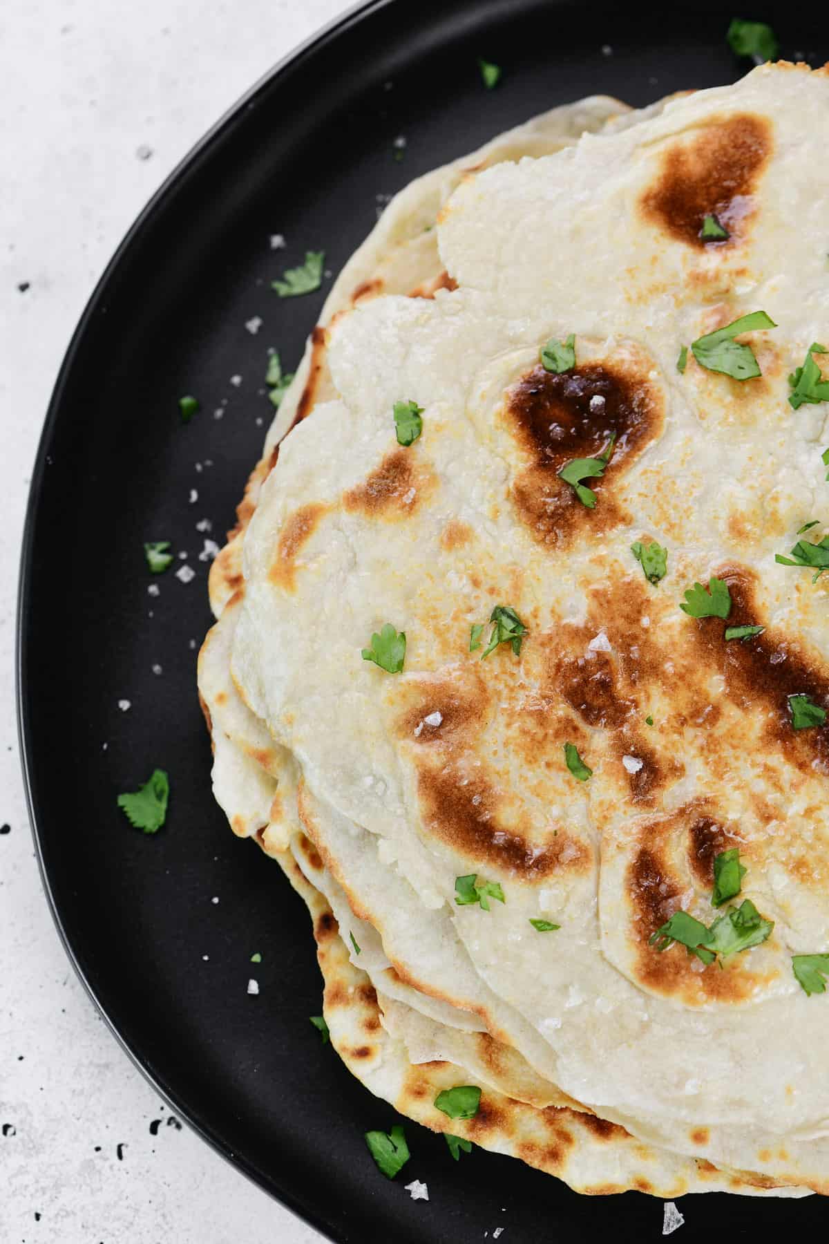 Cottage cheese naan flatbread on a black plate.