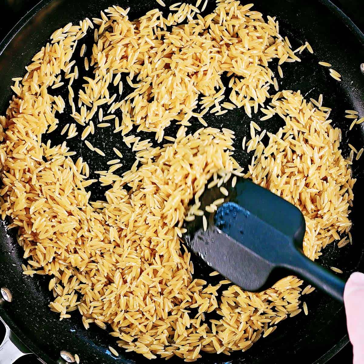 Toasting orzo in a skillet.