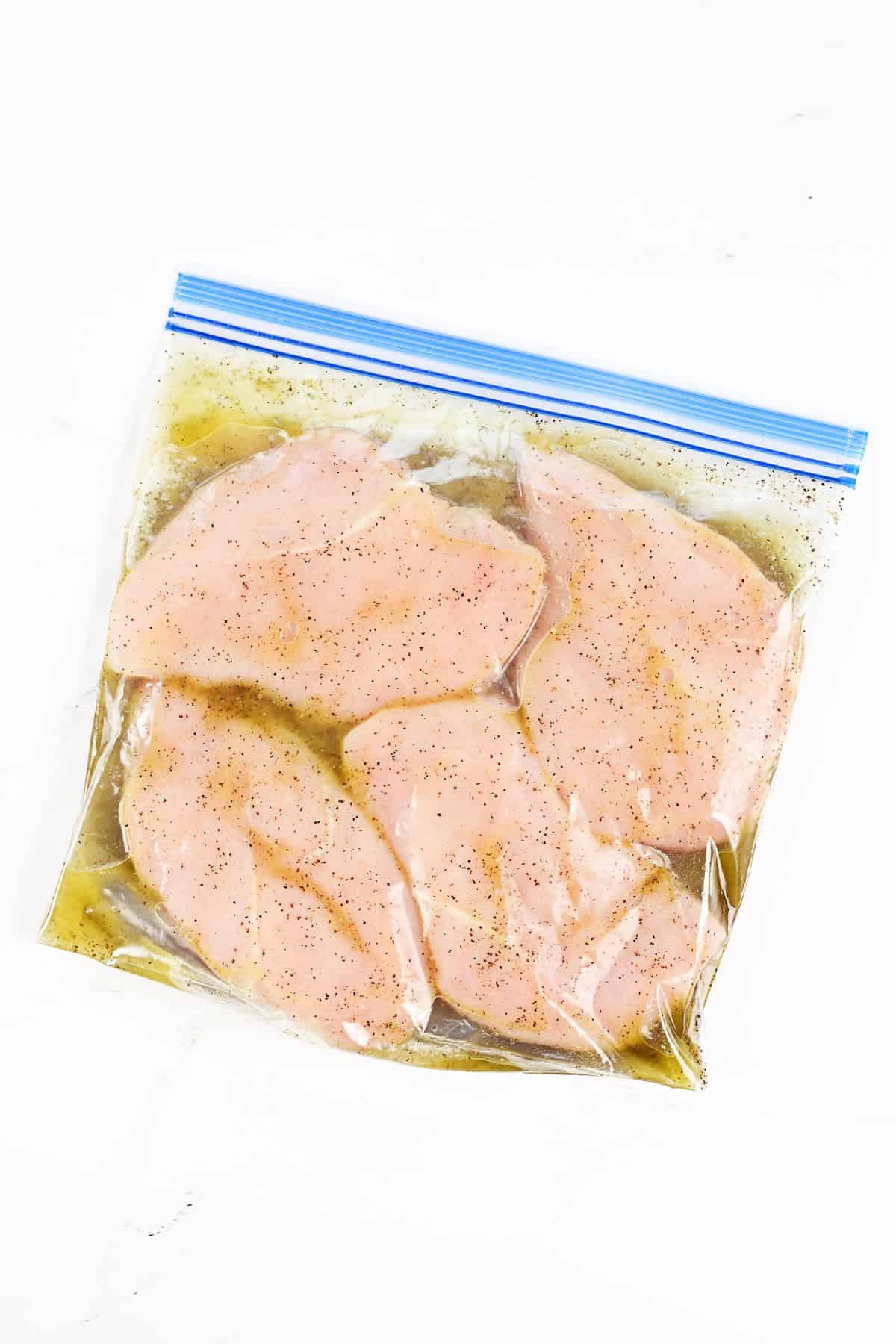 Greek chicken marinade on chicken breasts in a gallon sized ziptop bag.