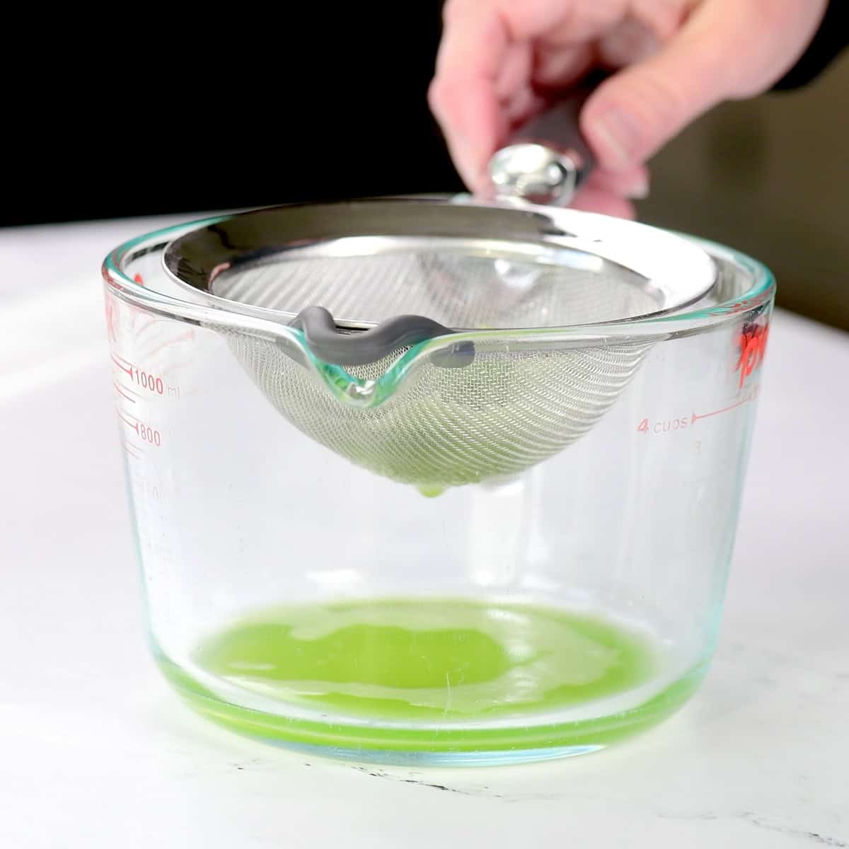 Draining green liquid through a strainer.