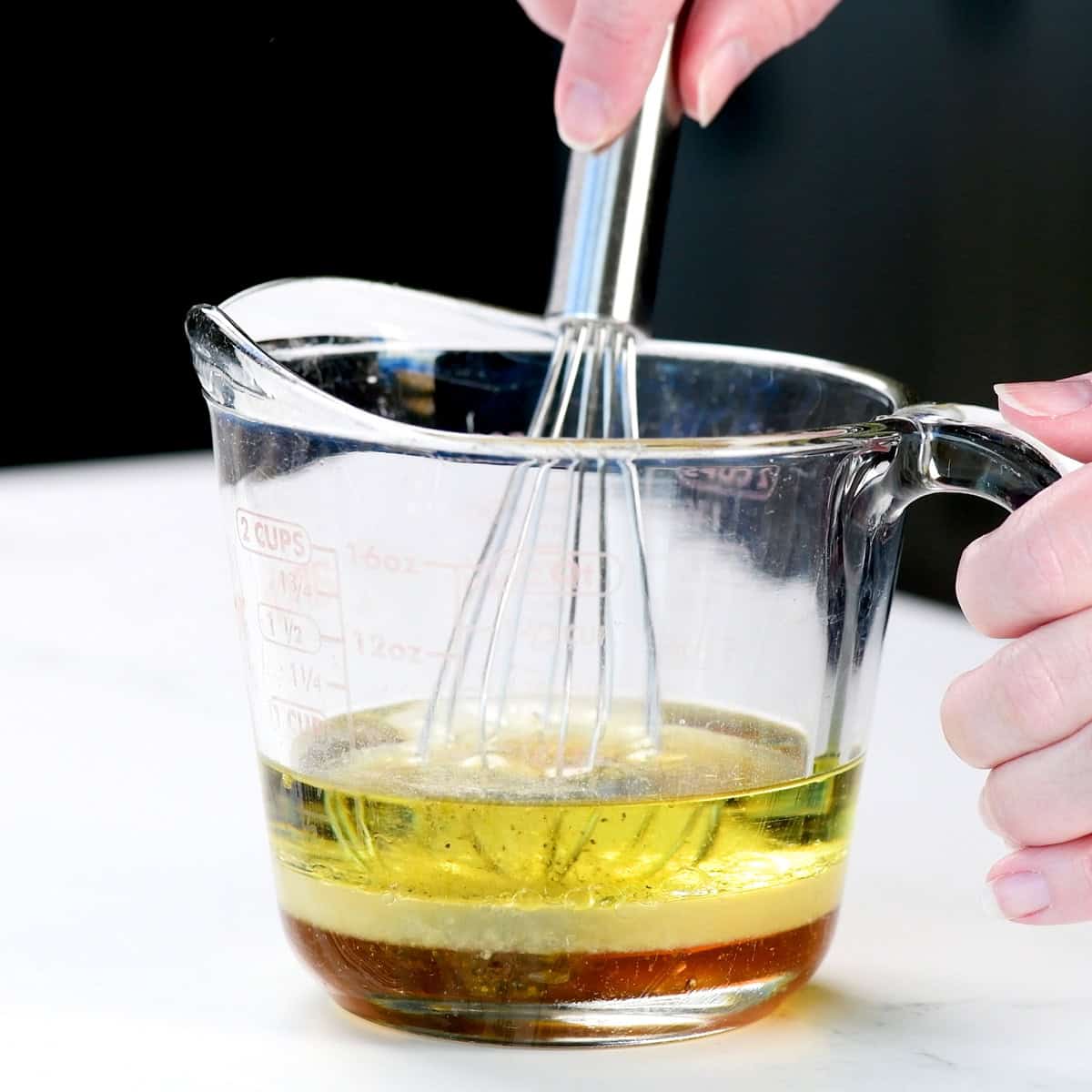 Whisking marinade ingredients in a small glass measuring cup.