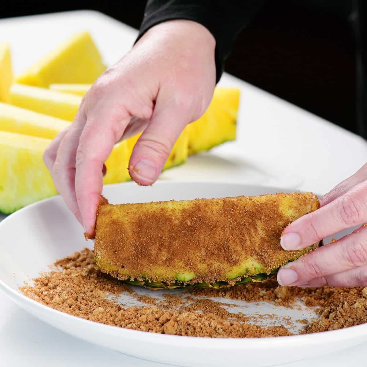 Adding brown sugar and spices to a piece of pineapple.