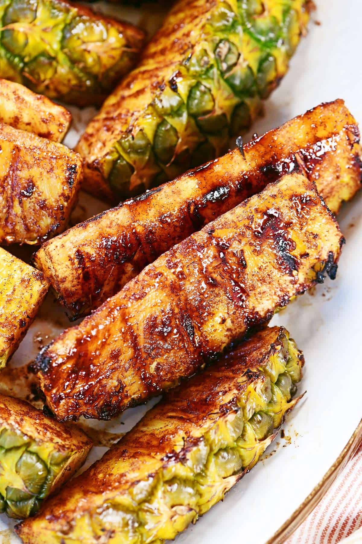 Grilled pineapple wedges on a white platter.