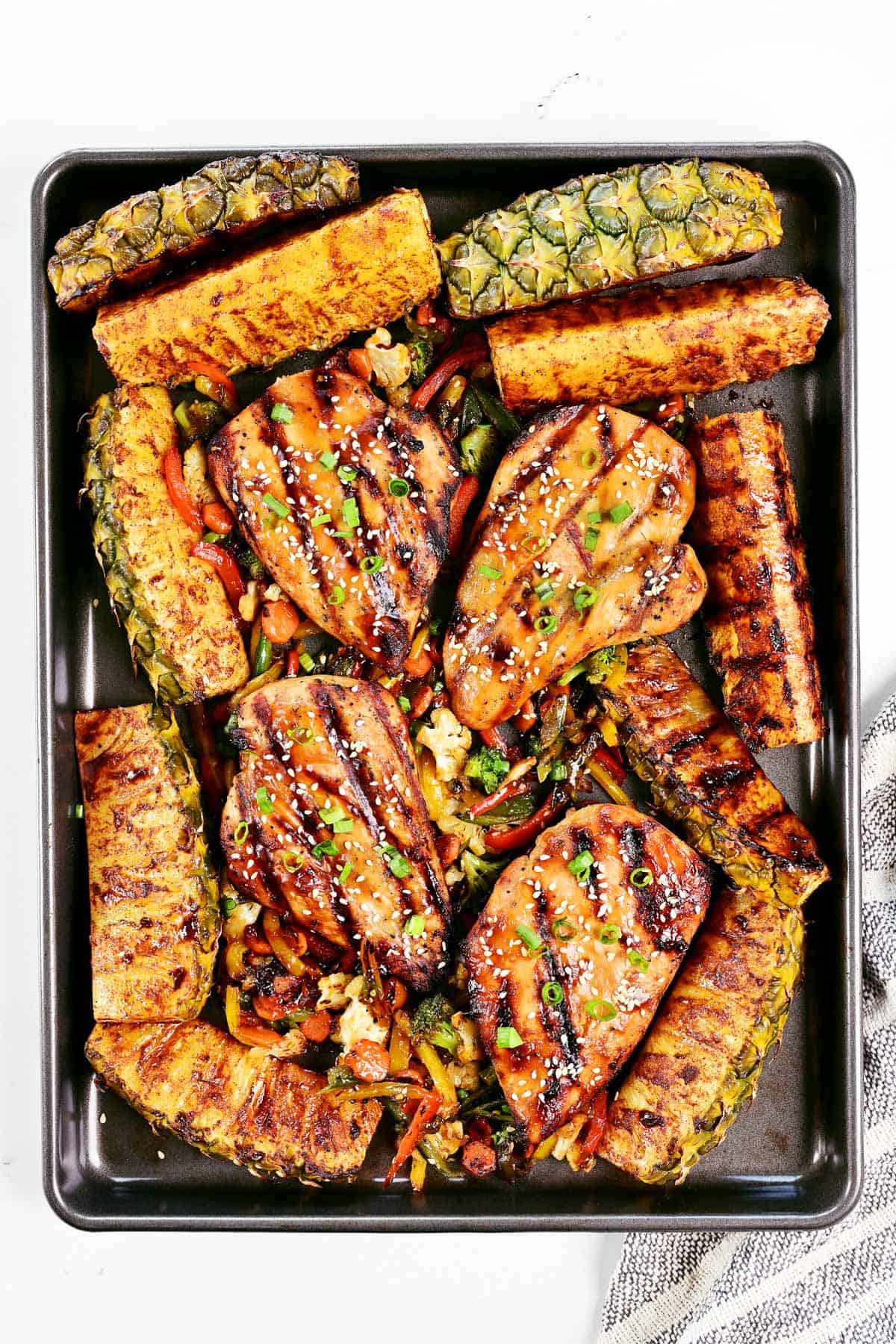 Teriyaki chicken marinade on chicken surrounded by grilled pineapple and stir fry veggies.