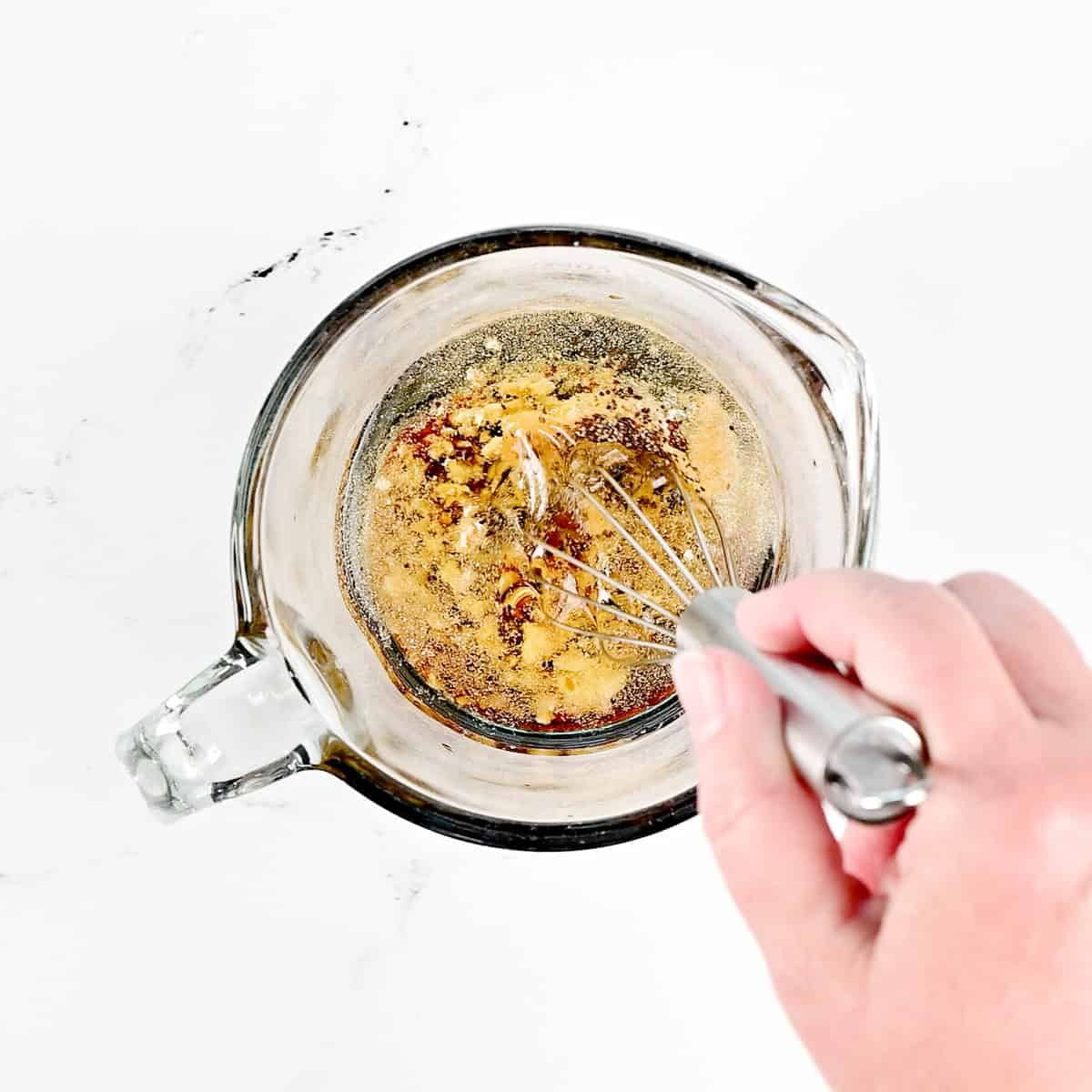 Whisking ingredients in a small glass measuring cup.