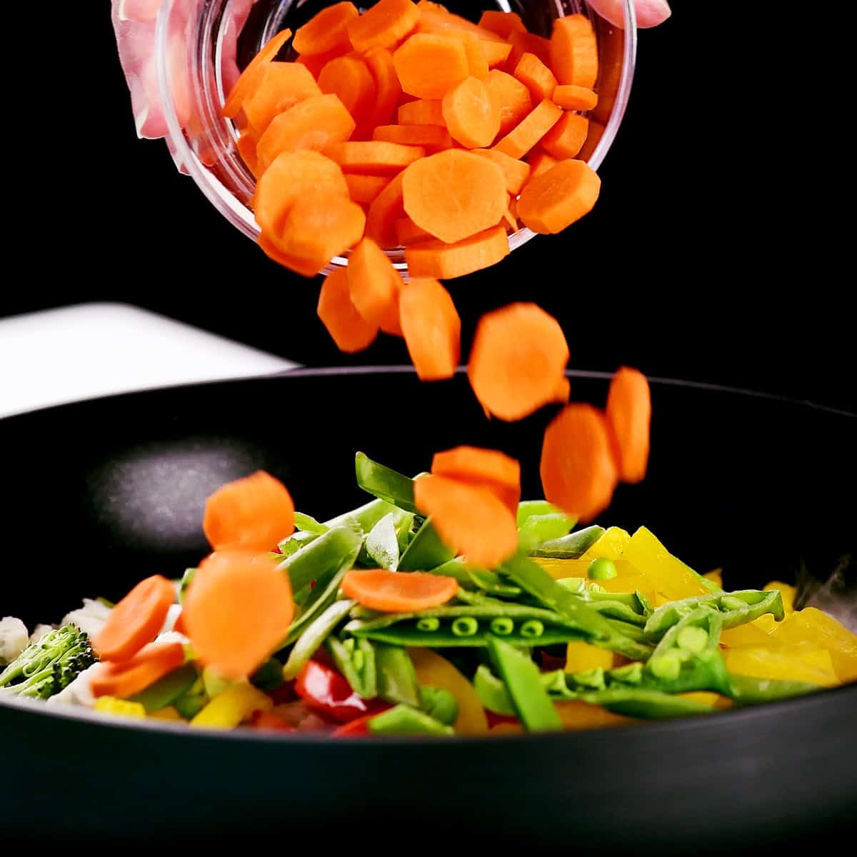 Adding sliced carrots to the pan.