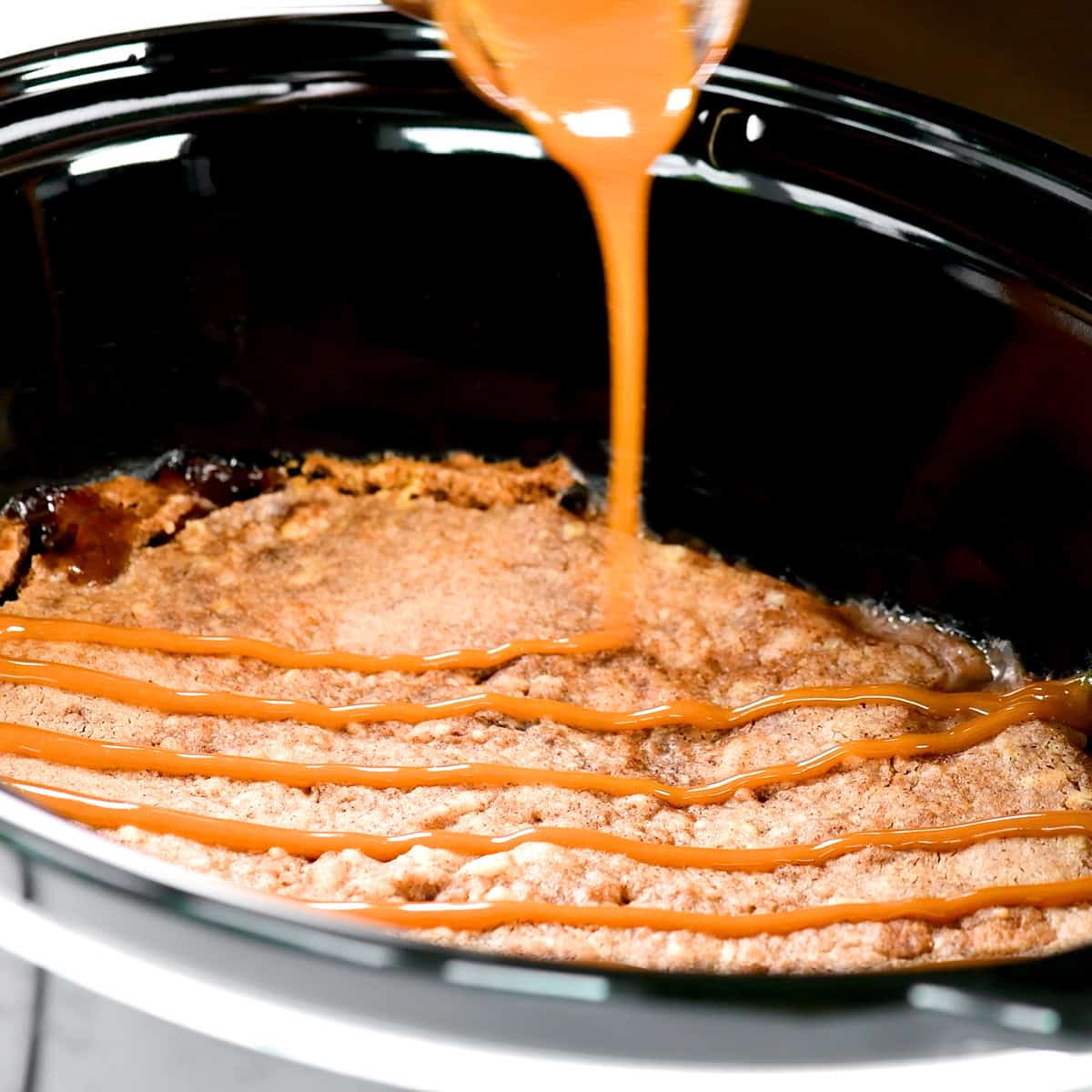 Drizzling caramel over the slow cooker apple dump cake.