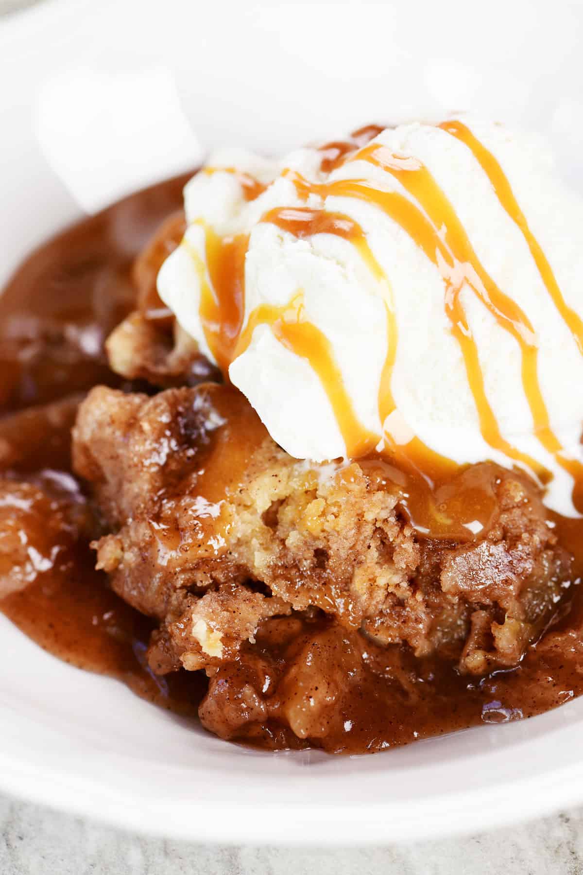 Crockpot apple dump cake with ice cream and caramel on top.