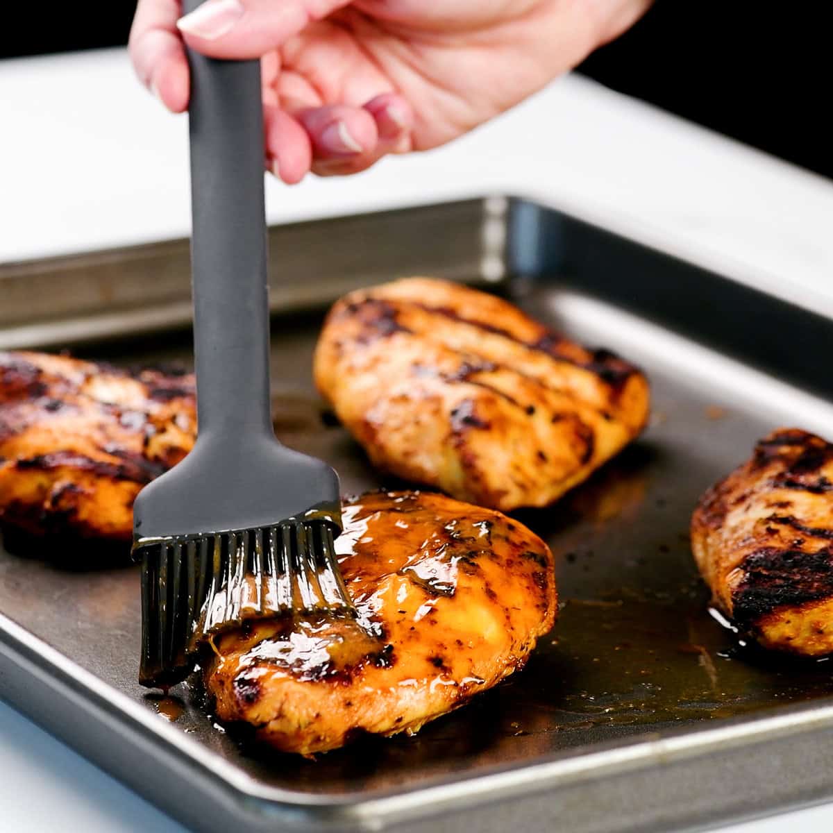 Basting buffalo chicken with buffalo sauce.