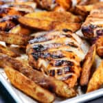 Buffalo chicken marinade grilled chicken on a sheet pan with potato wedges.